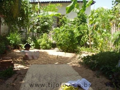 Quintal permacultural com círculo de bananeiras, com mamão, feijão, mandioca, batata, capim cidreira, acerola, hortelã, manjericão, dentre outras plantas, irrigadas com as águas da lavanderia e da pia da cozinha. O clima local é semi-árido. Limoeiro do Norte, Ceará.